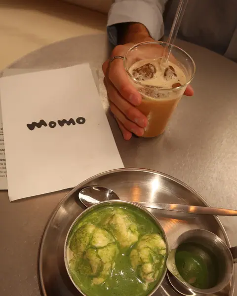 An iced matcha and an iced coffee on a steel tray with a momo napkin