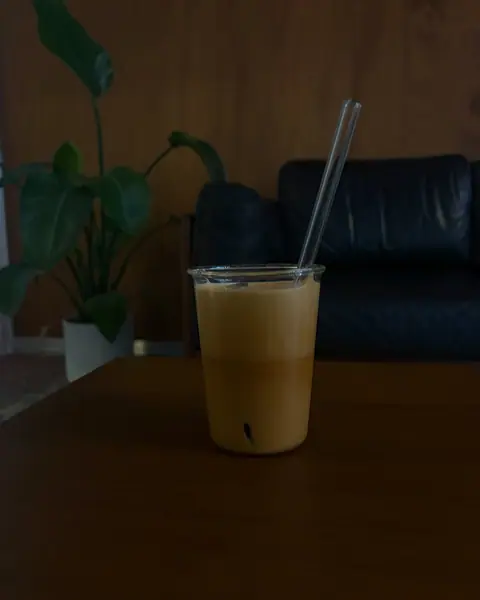 Iced Spanish latte on a wooden table beside a plant