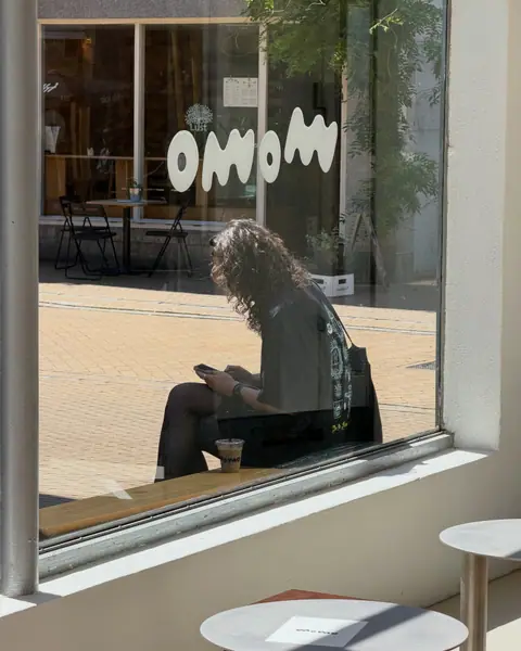 A guest reading at the window seat, the momo lettering on the glass
