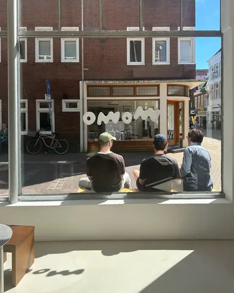 The street seen through the front window, guests on the bench outside